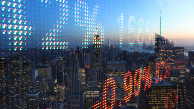 Stock market ticker data overlaid on top of a photo of the Manhattan skyline at sunrise.