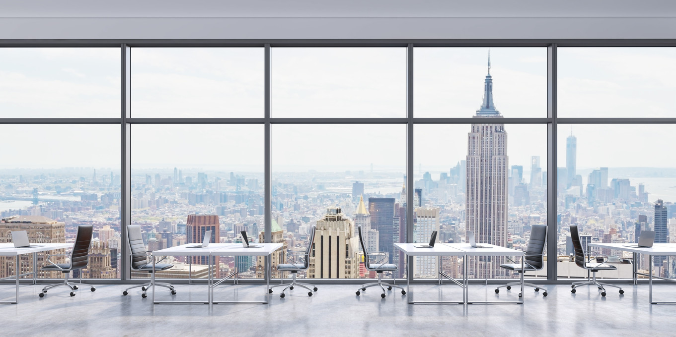 Workplaces in a modern panoramic office, New York city view in the windows, Manhattan. Open space. White tables and black leather chairs. A concept of financial consulting services.