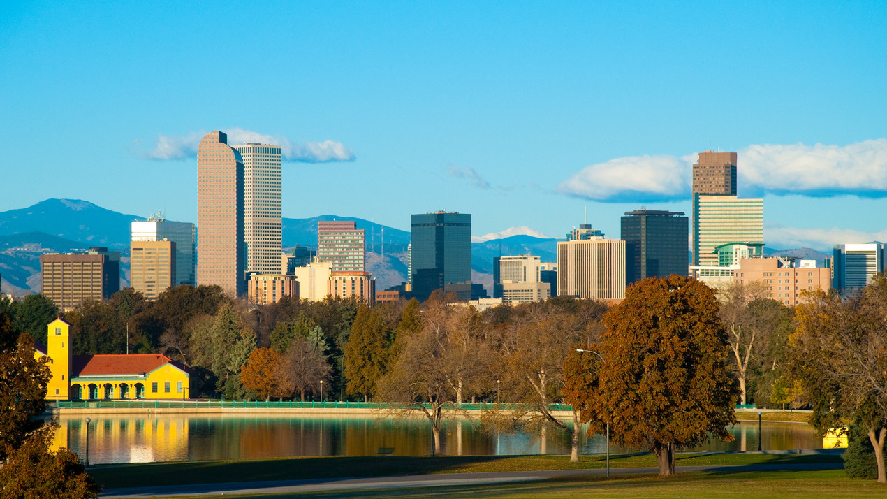 Denver downtown skyline in Autumn w/ City Park and lake in the foreground and the Rocky Mountains in the background.