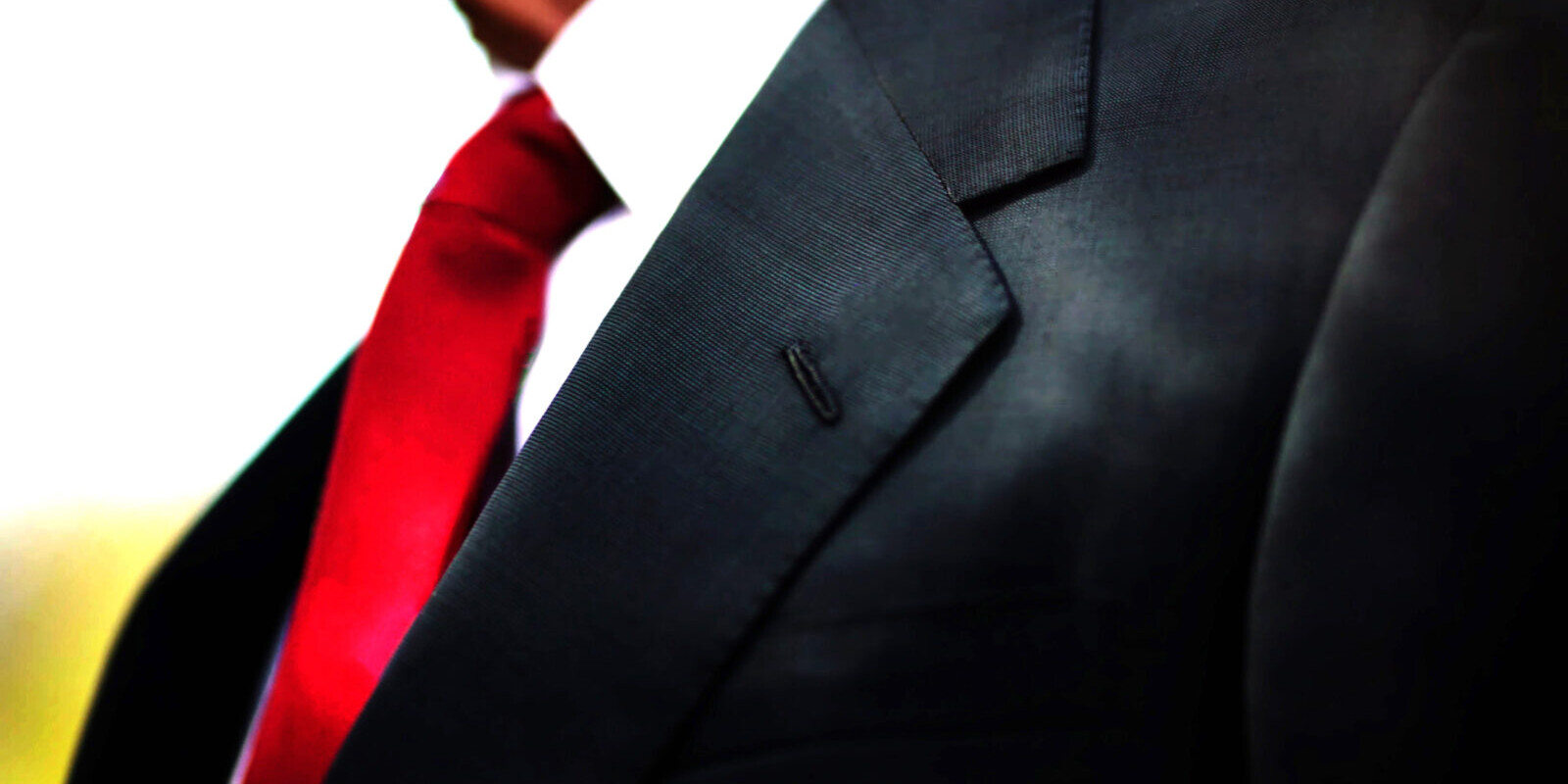 a black business suit jacket with white shirt and red tie, man n