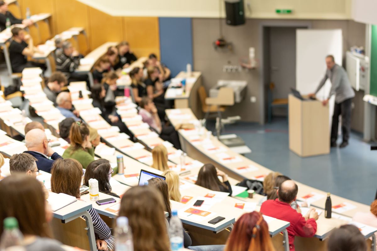 Audience seated in a university lecture hall.