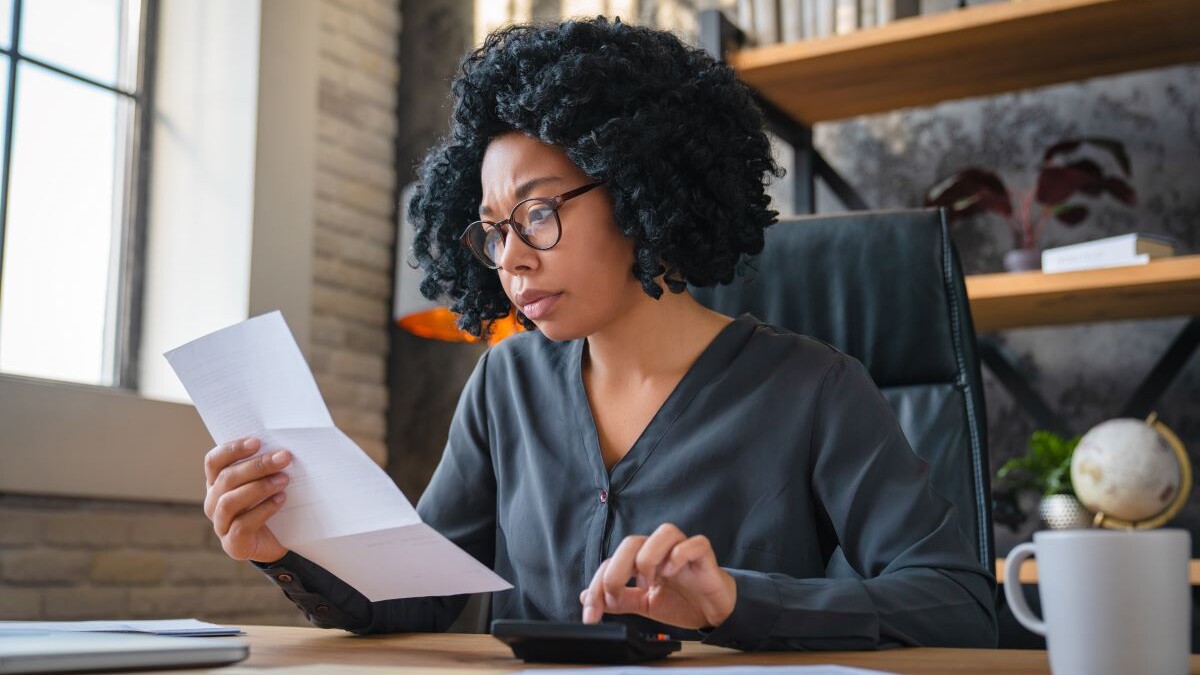 woman calculating finance, money, using calculator, laptop computer at home workplace table