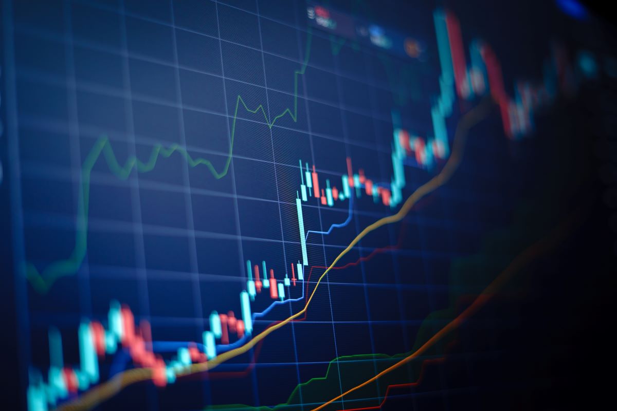 Closeup financial chart with uptrend line candlestick graph in stock market on blue color monitor background