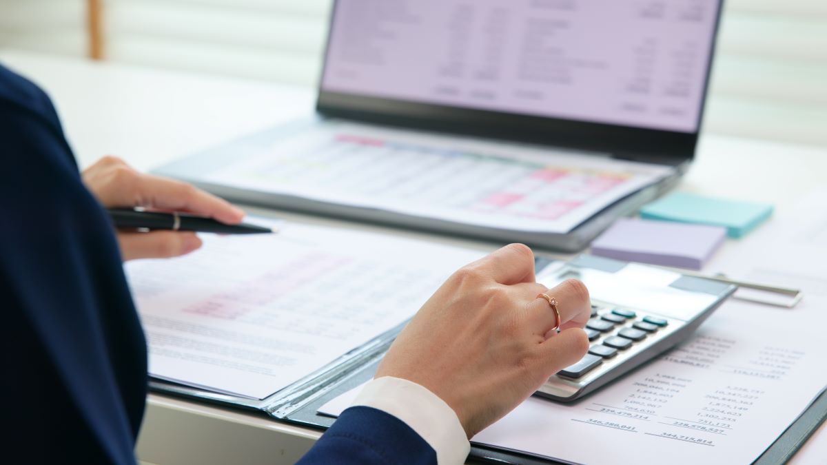 imageof female hand pressing calculator, reviewing financial documents on laptop