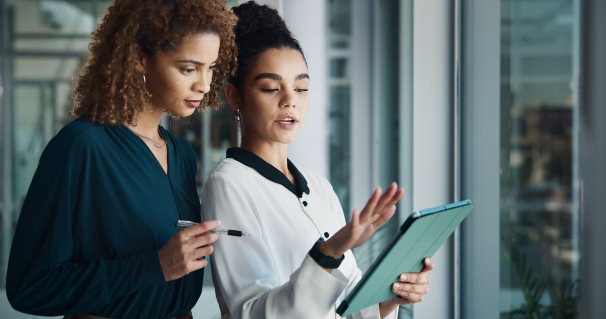 two women having a conversation while looking at an ipad