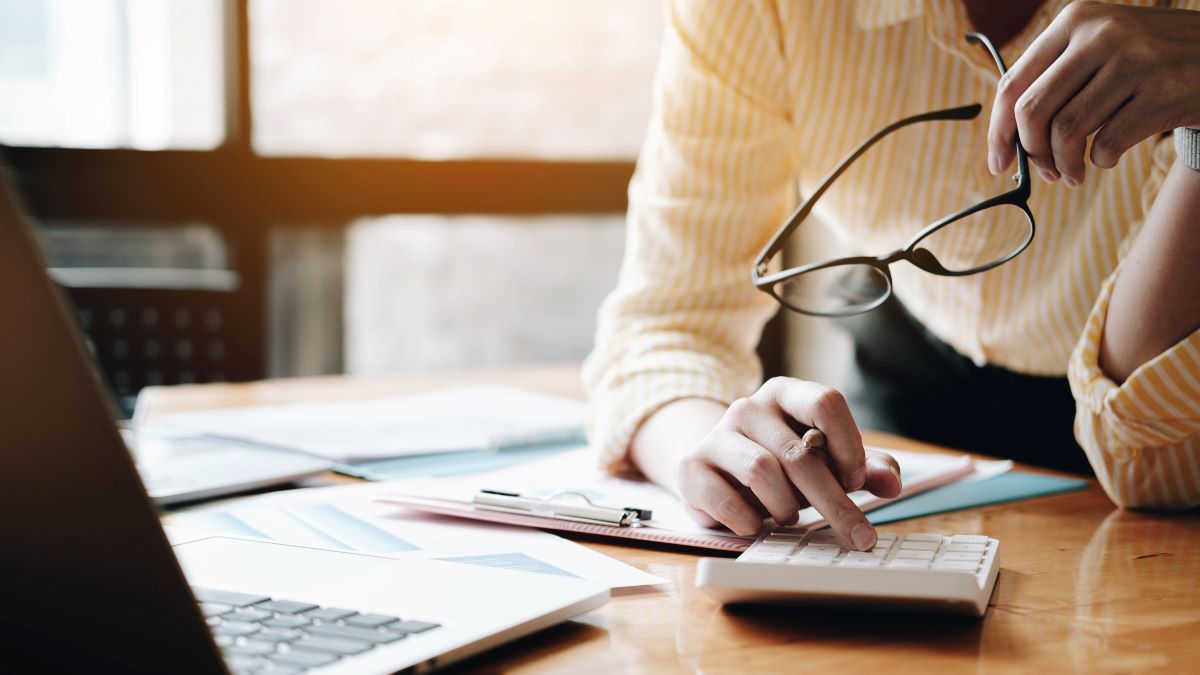 Close up Business woman using calculator and laptop for do math finance on wooden desk in office